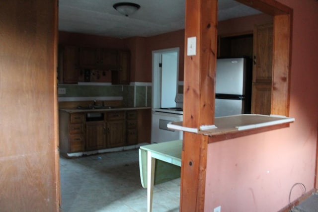 kitchen featuring kitchen peninsula, sink, stainless steel refrigerator, and range