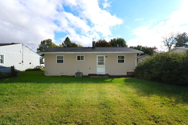 rear view of property featuring a lawn and central air condition unit