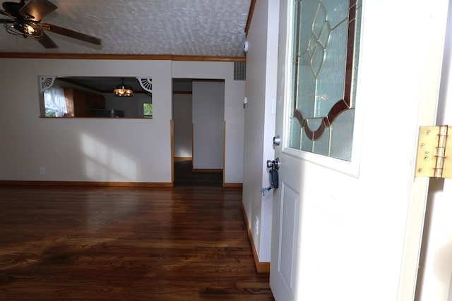 hallway with an inviting chandelier, dark wood-type flooring, a textured ceiling, and ornamental molding