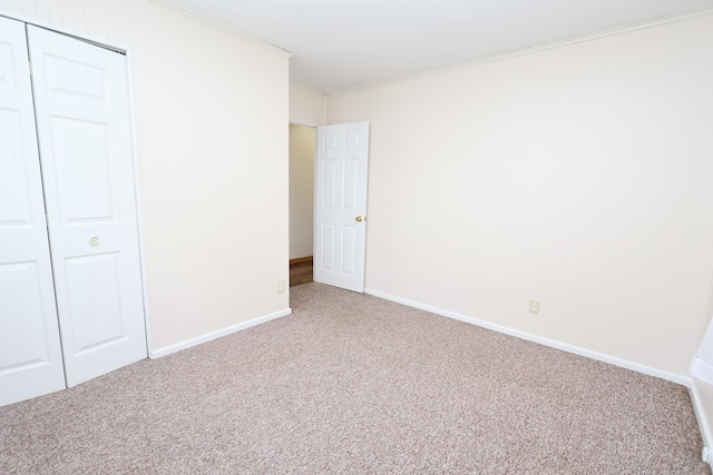 unfurnished bedroom featuring carpet flooring, ornamental molding, and a closet