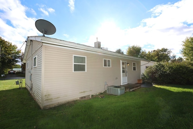 rear view of property featuring a lawn and central AC