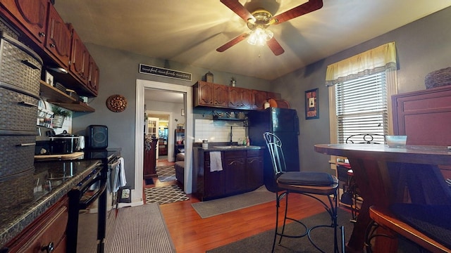 kitchen featuring black refrigerator, dark hardwood / wood-style flooring, backsplash, ceiling fan, and sink