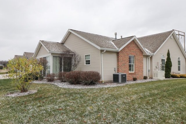 view of side of home featuring central AC unit, a sunroom, and a lawn