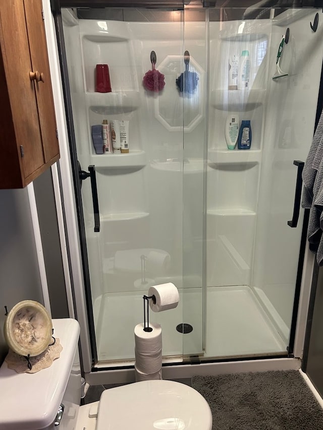 bathroom featuring a shower with shower door and toilet