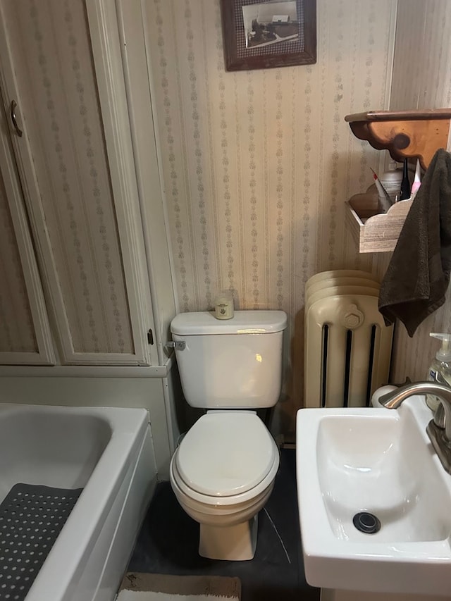 bathroom with a bathing tub, toilet, sink, and radiator