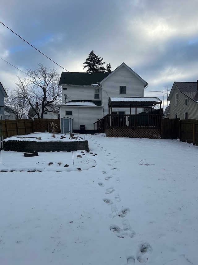 snow covered property with a shed and a deck