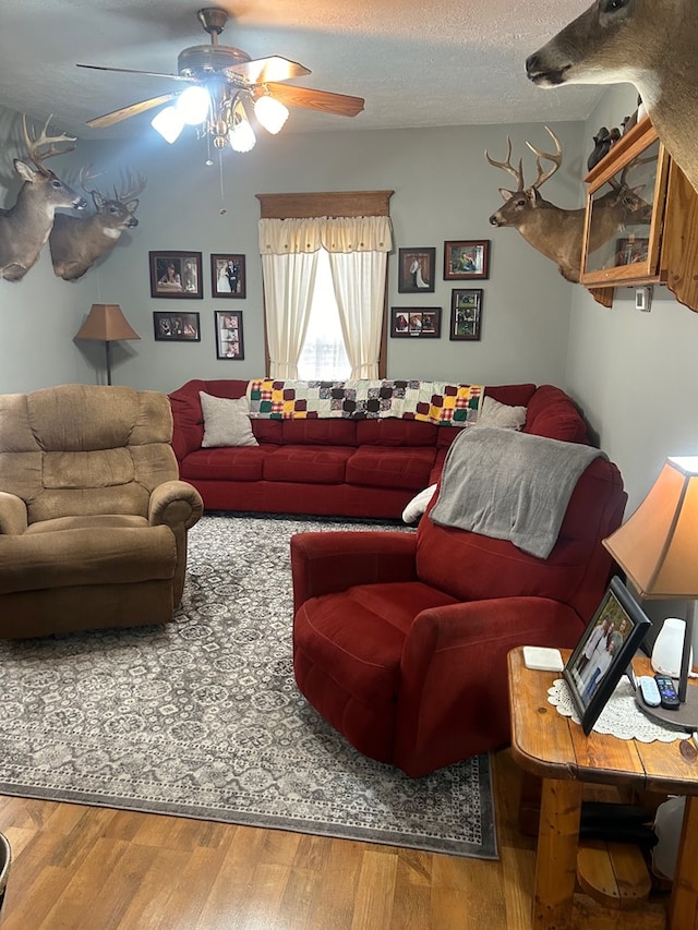 living room with ceiling fan, hardwood / wood-style floors, and a textured ceiling