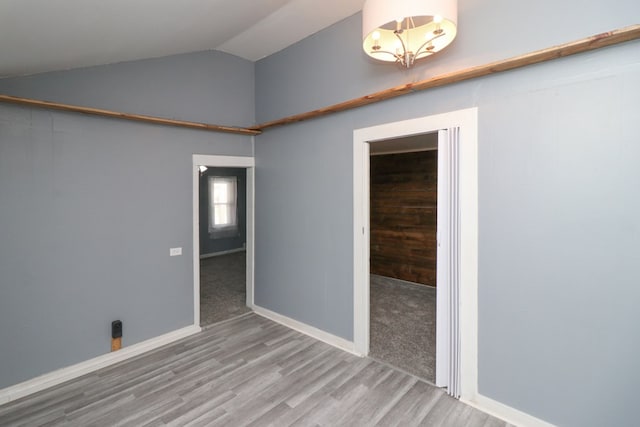 unfurnished room with hardwood / wood-style floors and vaulted ceiling