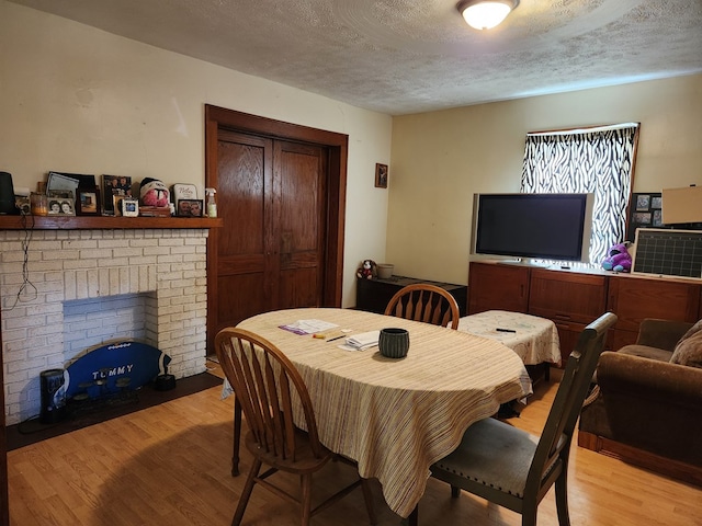 dining space featuring a fireplace, a textured ceiling, and wood finished floors