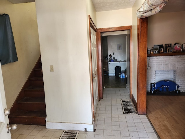 hall featuring light tile patterned floors, stairs, and visible vents