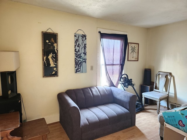 living room with a textured ceiling, baseboards, and wood finished floors