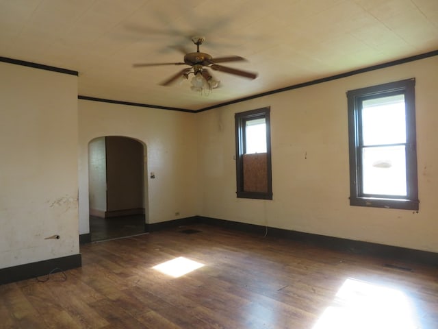 875 E Walnut St, Galion, OH 44833 - unfurnished room featuring arched walkways, crown molding, wood finished floors, ceiling fan, and baseboards