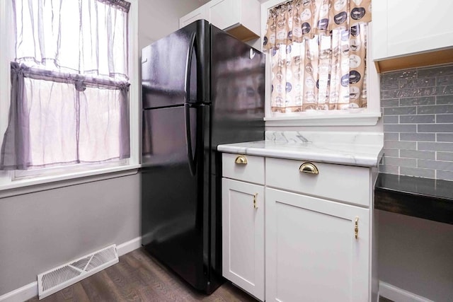 kitchen featuring black fridge, white cabinetry, dark wood-type flooring, and tasteful backsplash