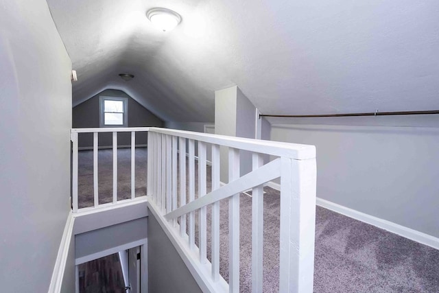 stairs with a textured ceiling, carpet floors, and vaulted ceiling