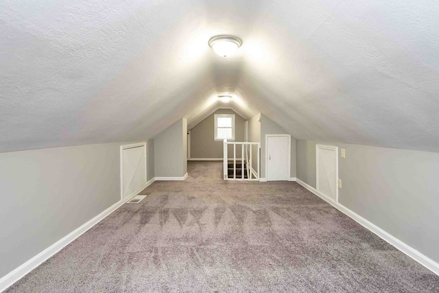 additional living space with carpet flooring, a textured ceiling, and vaulted ceiling