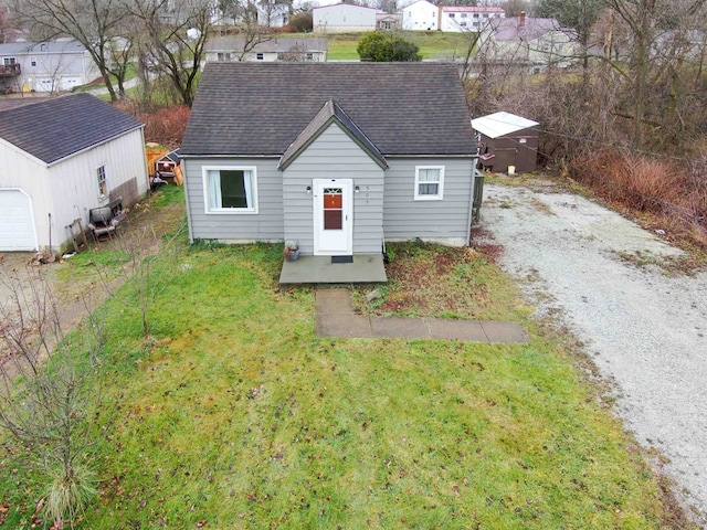 view of front facade featuring a garage, a front lawn, and an outdoor structure