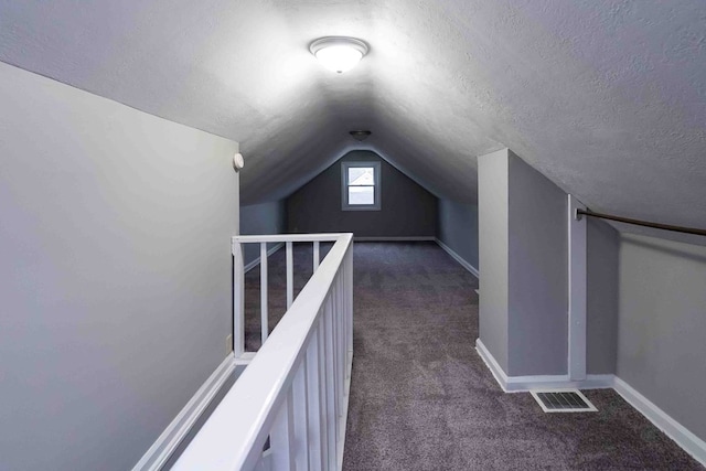 bonus room featuring dark colored carpet, a textured ceiling, and vaulted ceiling