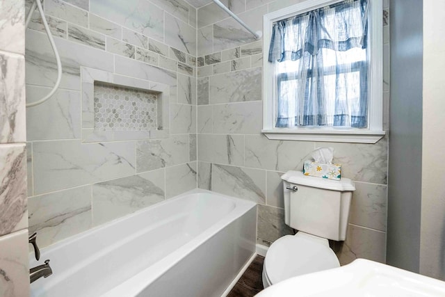 bathroom featuring wood-type flooring, tiled shower / bath combo, and toilet