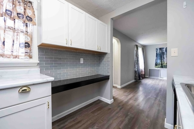 kitchen featuring a textured ceiling, tasteful backsplash, white cabinetry, and dark wood-type flooring