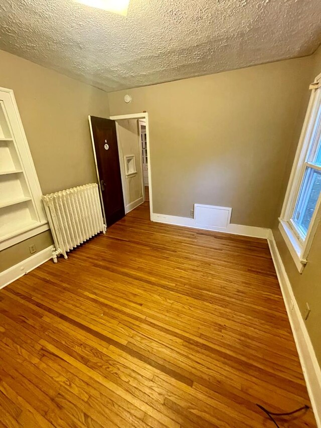 242 Davis Rd, Mansfield, OH 44907 - unfurnished room with radiator, wood-type flooring, a textured ceiling, and baseboards