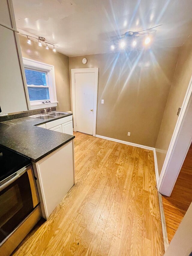242 Davis Rd, Mansfield, OH 44907 - kitchen featuring dark countertops, a sink, white cabinets, light wood-style flooring, and rail lighting