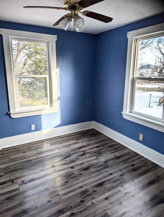 empty room with dark wood-type flooring, plenty of natural light, and ceiling fan