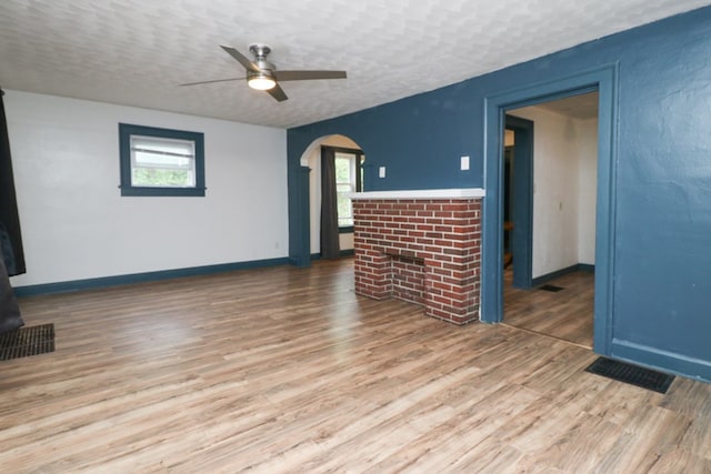 460 W Dickson, Mansfield, OH 44903 - unfurnished living room with a brick fireplace, ceiling fan, wood finished floors, arched walkways, and a textured ceiling
