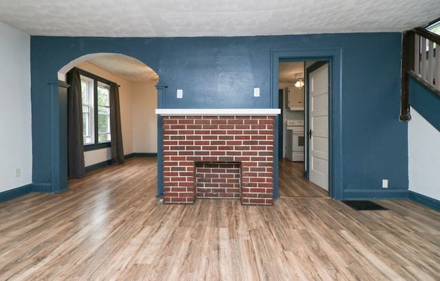 460 W Dickson, Mansfield, OH 44903 - unfurnished living room featuring wood finished floors, arched walkways, a fireplace, a textured ceiling, and stairs