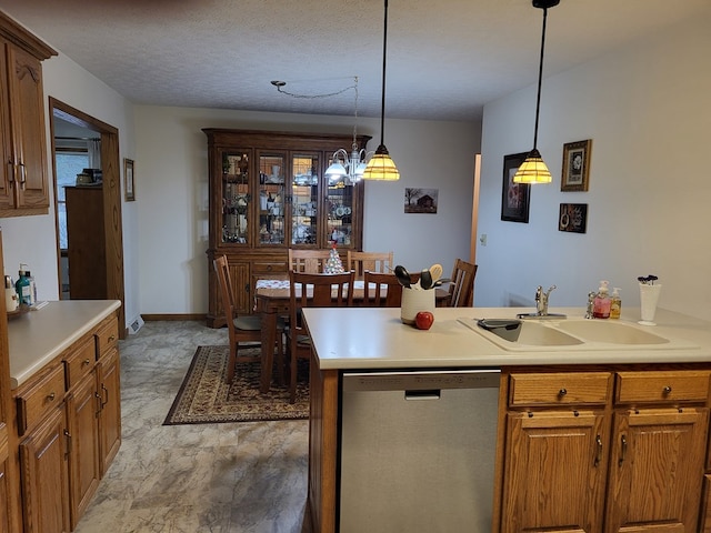 kitchen featuring stainless steel dishwasher, pendant lighting, sink, and a textured ceiling