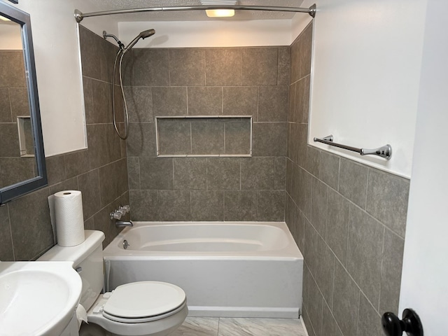 full bath featuring toilet, marble finish floor, a sink, tile walls, and washtub / shower combination