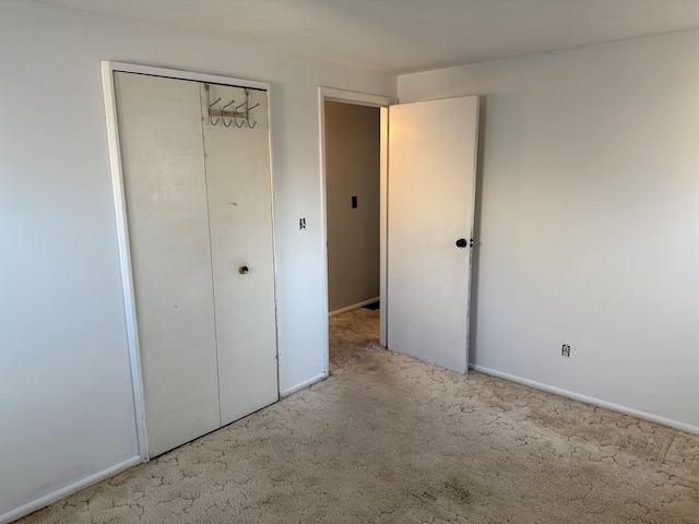 unfurnished bedroom with a closet, carpet flooring, and baseboards