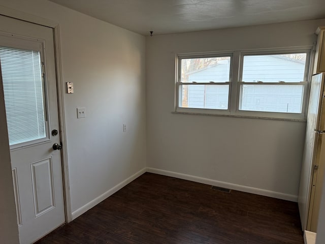 empty room featuring dark wood finished floors, baseboards, and visible vents