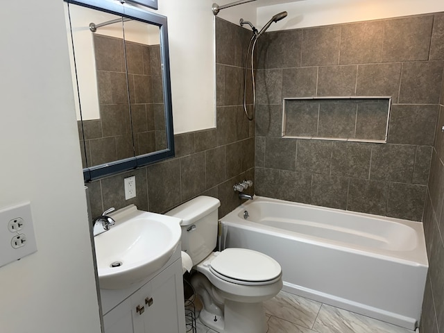 bathroom featuring toilet, marble finish floor, shower / washtub combination, tile walls, and vanity