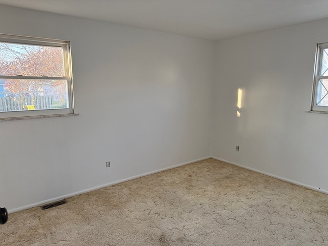 carpeted spare room with visible vents and baseboards