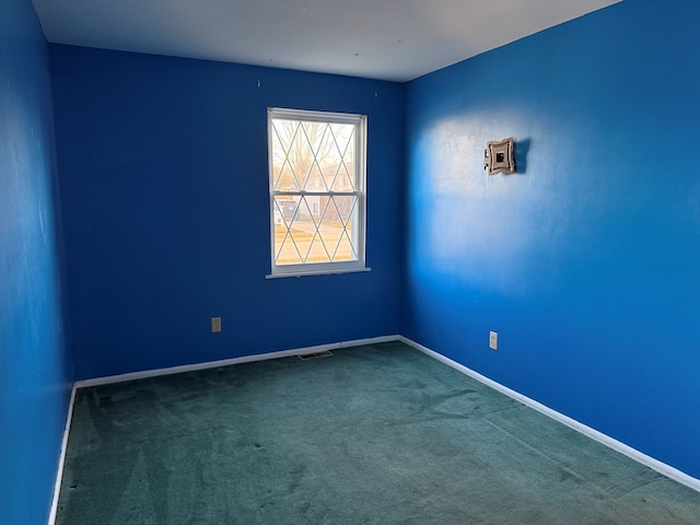 empty room with carpet flooring, visible vents, and baseboards