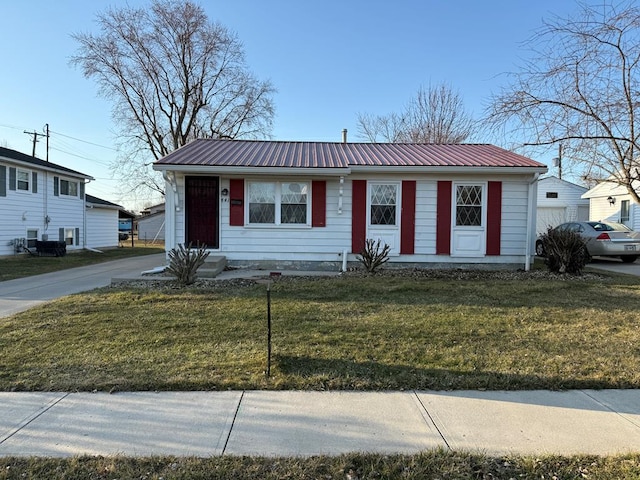 view of front of home with metal roof and a front lawn