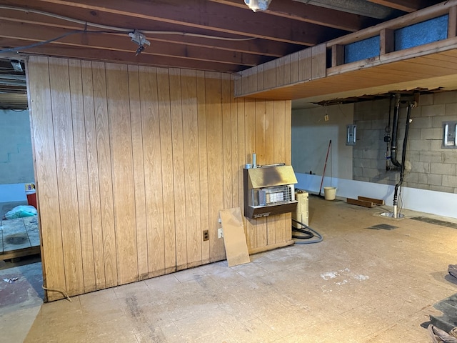 finished basement featuring electric panel, wooden walls, and concrete block wall