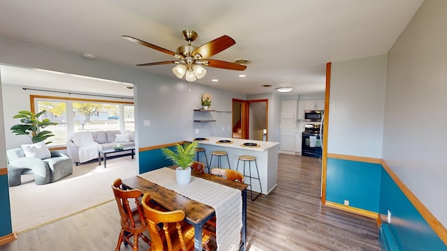 dining area featuring hardwood / wood-style floors, ceiling fan, and a baseboard heating unit