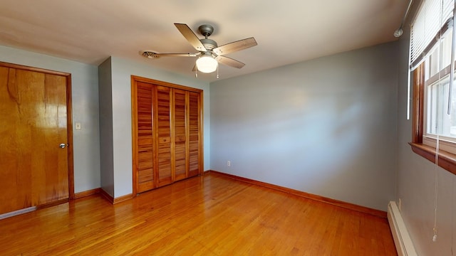 unfurnished bedroom featuring light hardwood / wood-style floors, baseboard heating, and ceiling fan