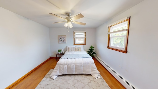 bedroom with hardwood / wood-style floors, baseboard heating, and ceiling fan