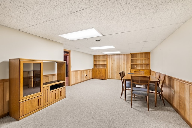 carpeted dining room with a paneled ceiling and built in features