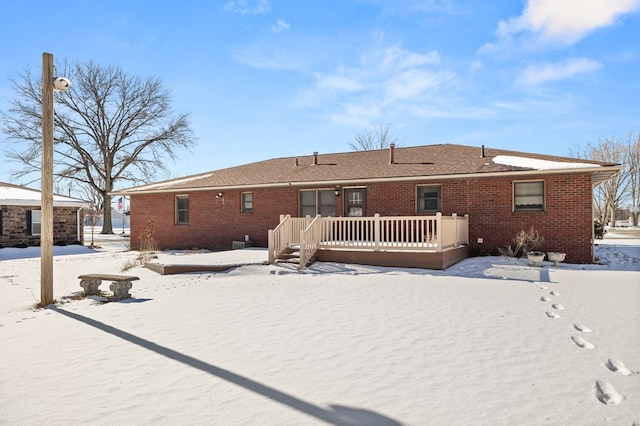 snow covered back of property featuring a wooden deck