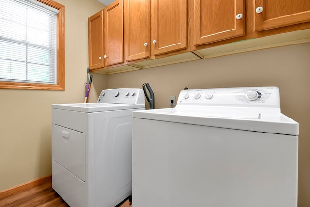 clothes washing area with cabinets, hardwood / wood-style floors, and washer and dryer