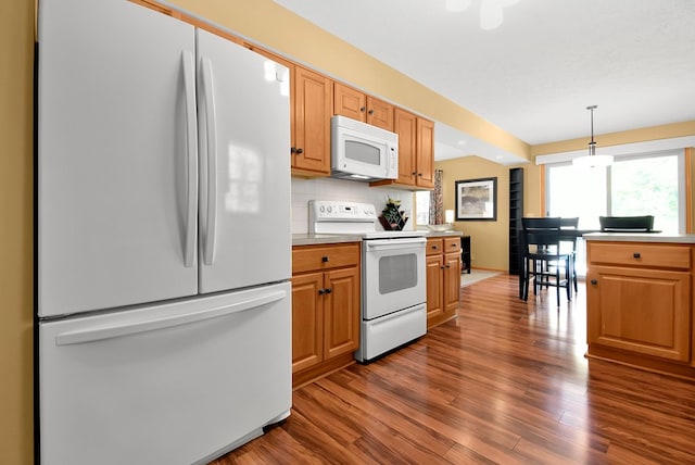 kitchen with decorative light fixtures, dark hardwood / wood-style flooring, white appliances, and tasteful backsplash