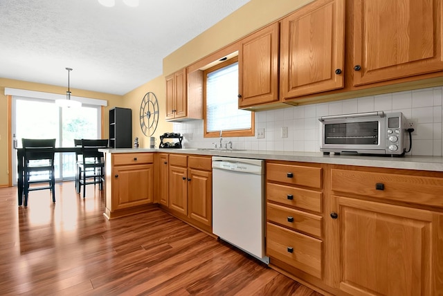 kitchen with a textured ceiling, sink, pendant lighting, hardwood / wood-style flooring, and dishwasher