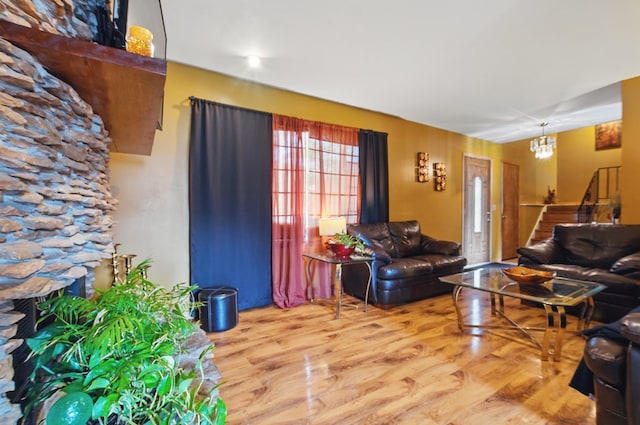 living room featuring stairway, an inviting chandelier, a fireplace, and wood finished floors