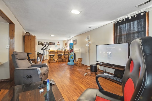 living room featuring baseboards, visible vents, and wood finished floors