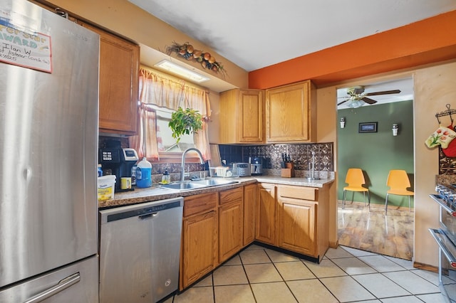 kitchen with decorative backsplash, ceiling fan, a sink, stainless steel appliances, and light tile patterned flooring