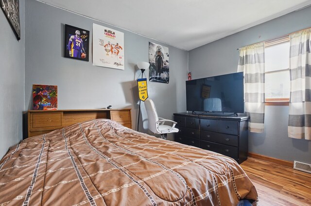 bedroom featuring baseboards, visible vents, and wood finished floors