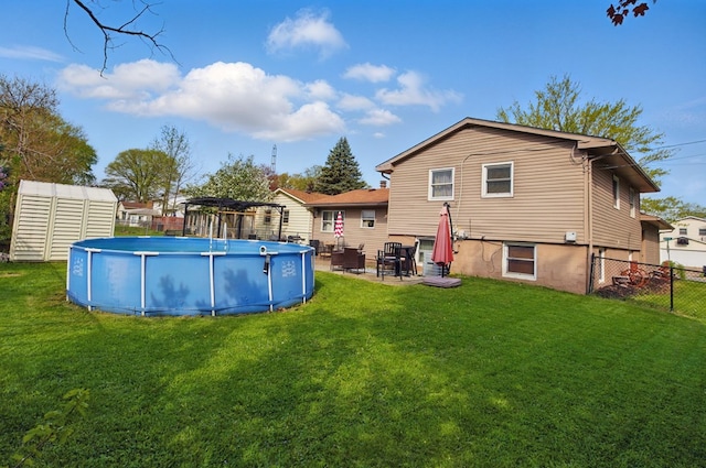 rear view of house featuring fence, a yard, and an outdoor pool
